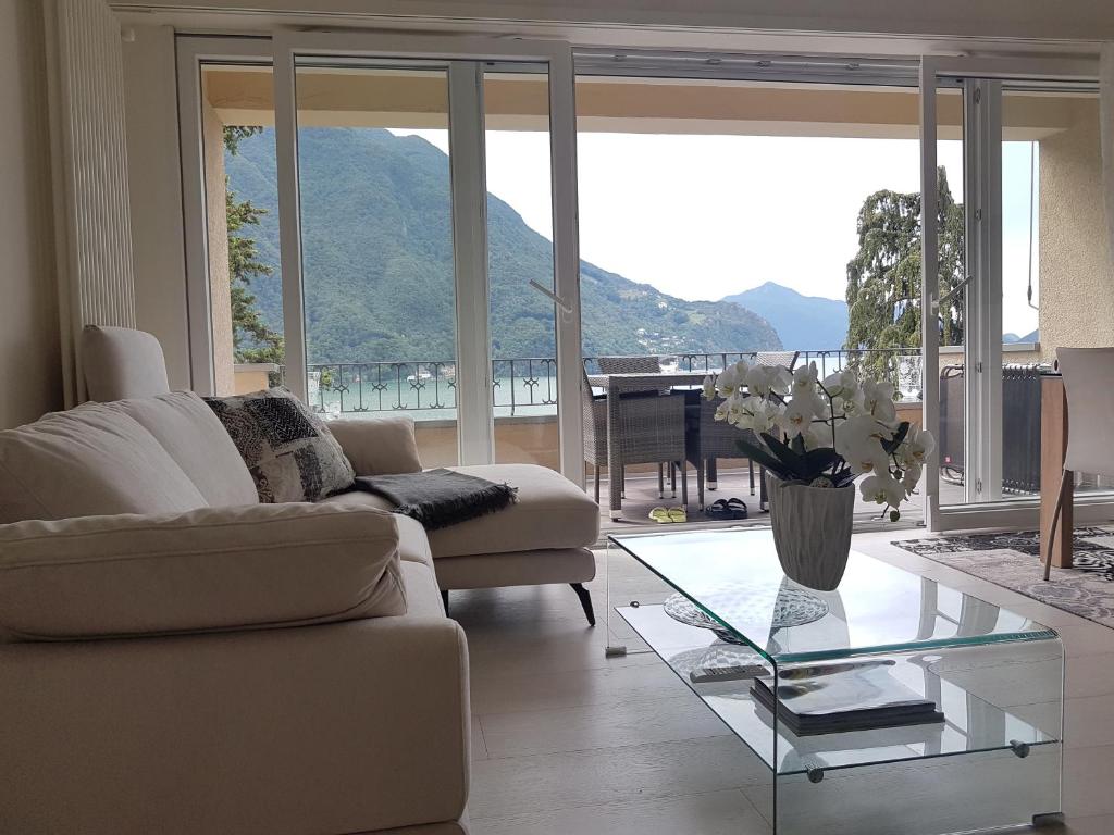 un soggiorno con divano e tavolo in vetro di Villa Violetta - Bellavista a Castagnola