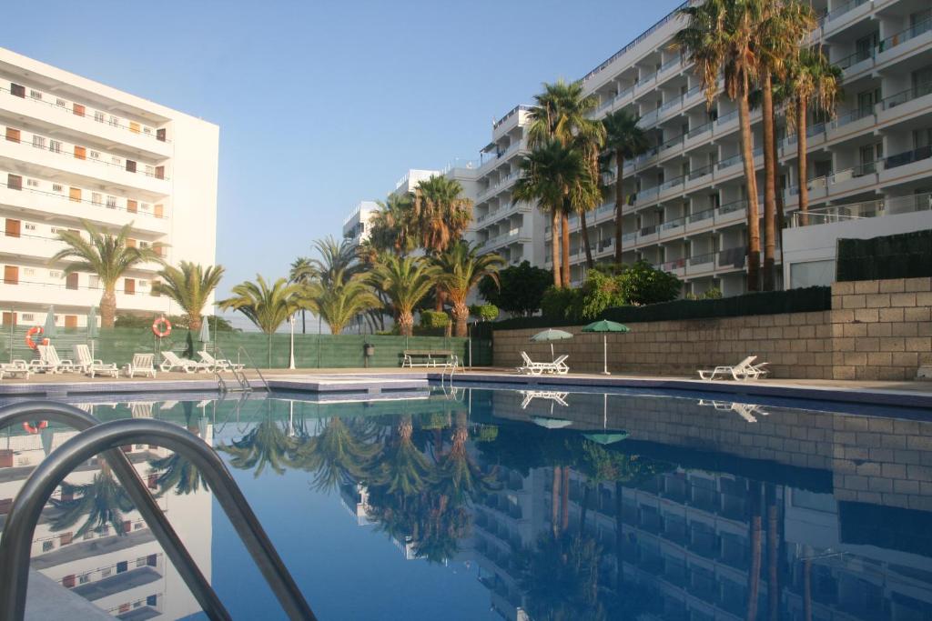 una piscina con palmeras y un edificio en Apartamento Vacacional Playa, en Playa de las Américas