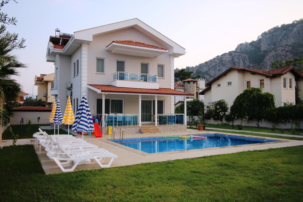 a house with a swimming pool and two lawn chairs at Dalyan Villa MoonLight in Dalyan