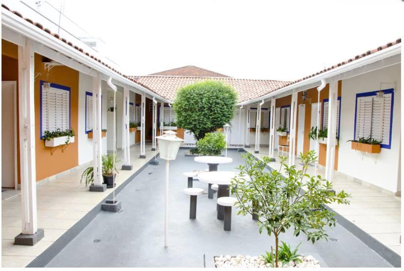 a corridor of a building with tables and plants at Hotel Gandhi in Jacutinga