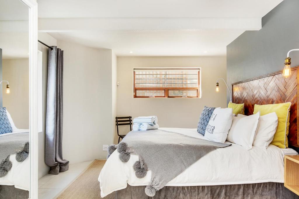a bedroom with a bed with white and blue pillows at Cheviot Place Garden Apartment with Private Entrance in Cape Town
