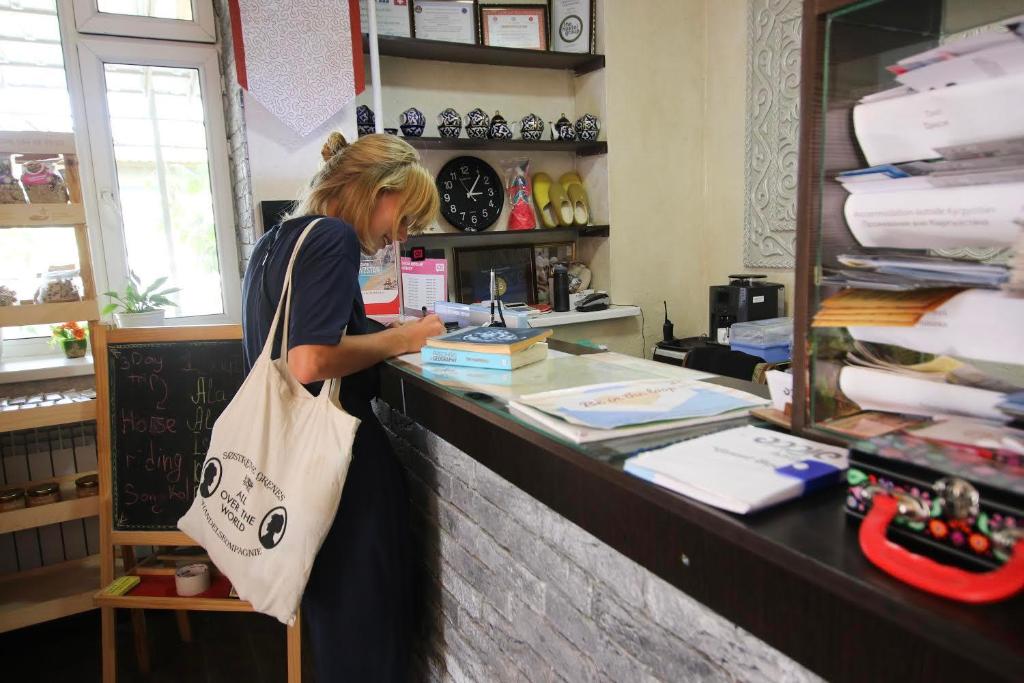 a woman standing at a counter in a store at Apple Hostel Bishkek in Bishkek