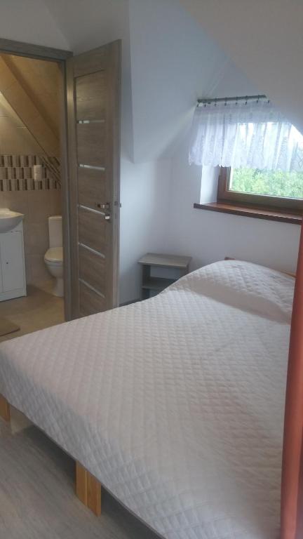 a bedroom with a white bed and a bathroom at Noclegi nad lasem in Gliczarów