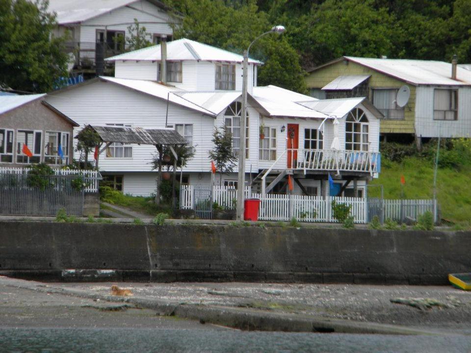 a white house with a fence in front of houses at Hostal Guarida del Trauco in Puqueldón