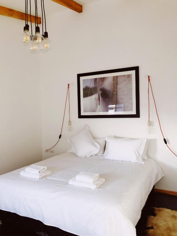 a white bed with white pillows and a picture on the wall at El Establo in Puerto Natales