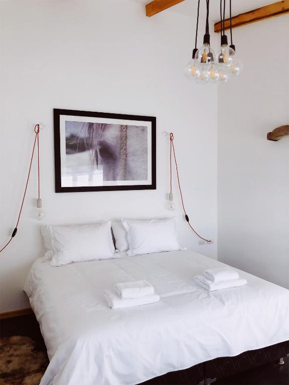 a white bed with white pillows and a picture on the wall at El Establo in Puerto Natales