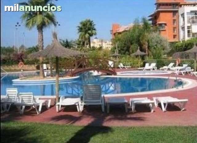 - une piscine avec des chaises et des parasols dans un complexe dans l'établissement Las Dunas De Islantilla, à Islantilla