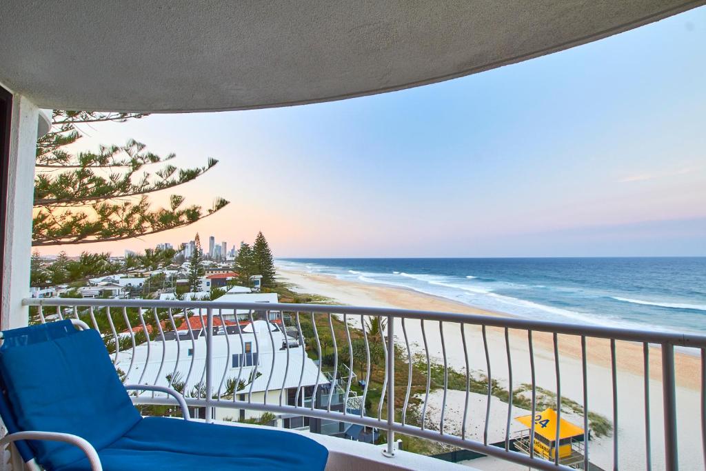 uma varanda com uma cadeira azul e a praia em Albatross North Apartments em Gold Coast