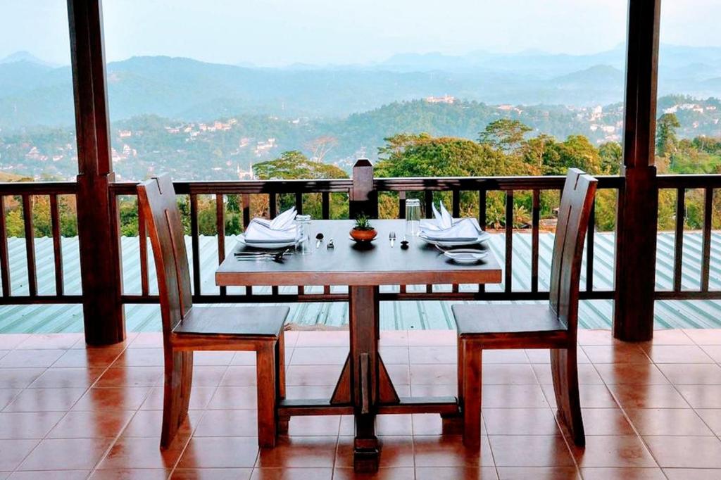 Kandy Unique Hotel في كاندي: طاولة وكراسي على شرفة مطلة