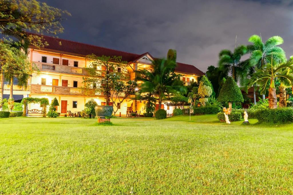 a large building with a green lawn in front of it at PN Gold Resort in Bangsaen