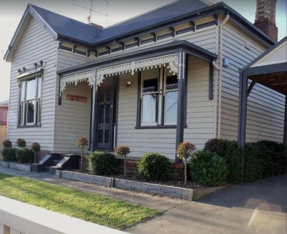 a white house with a porch with trees in it at Eureka Views B&B Ballarat in Ballarat