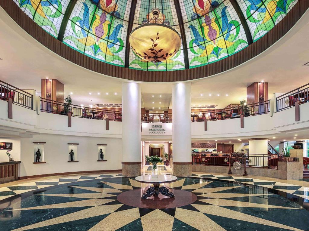 a large lobby with a large stained glass ceiling at Mercure Jakarta Kota in Jakarta