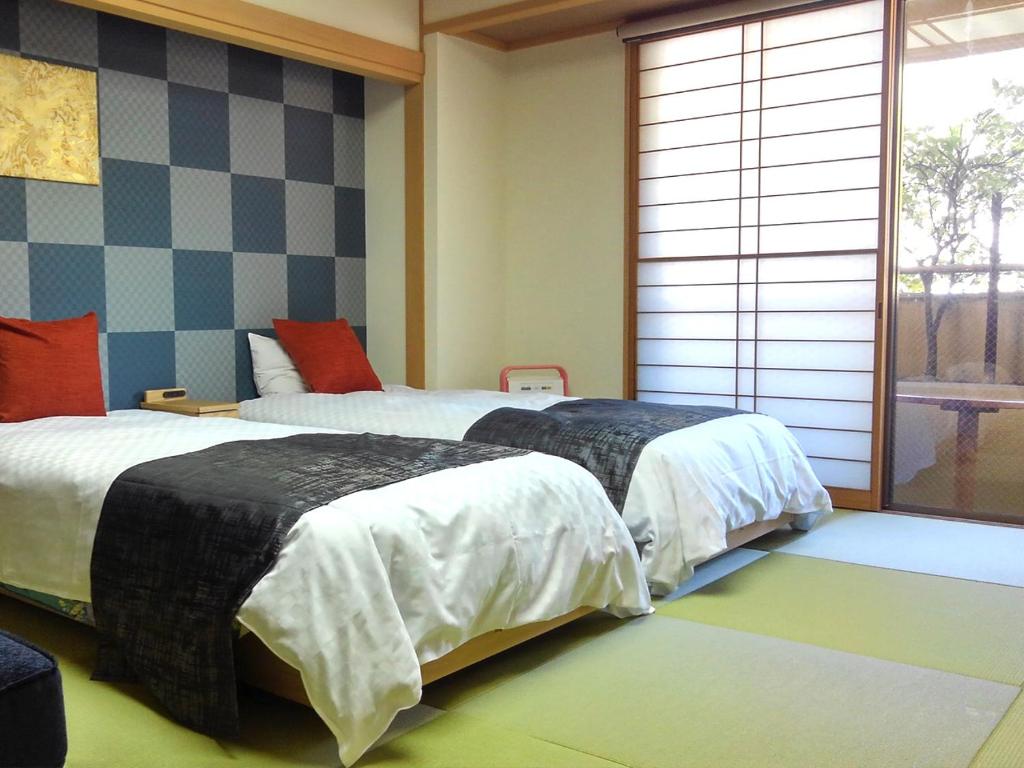 een slaapkamer met 2 bedden en een raam bij Hanayuzuki in Matsuyama