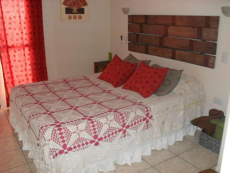 a bedroom with a bed with red pillows at Los Lapachos in San Miguel de Tucumán