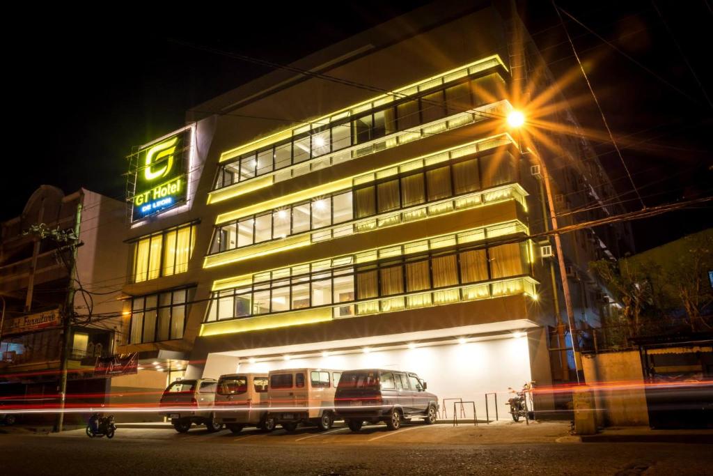 un bâtiment avec des voitures garées devant lui la nuit dans l'établissement GT Hotel Iloilo, à Iloilo