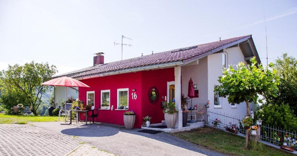 a red and white house with a table in front of it at Ferienwohnung Streifinger in Freyung