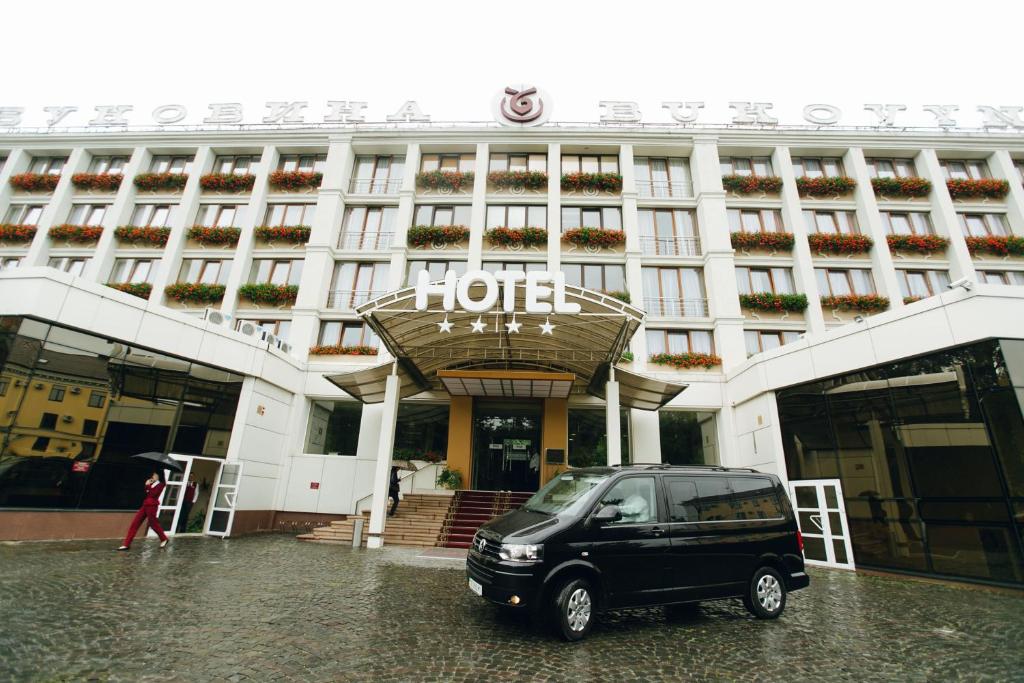 uma carrinha preta estacionada em frente a um hotel em Bukovyna Hotel em Chernivtsi