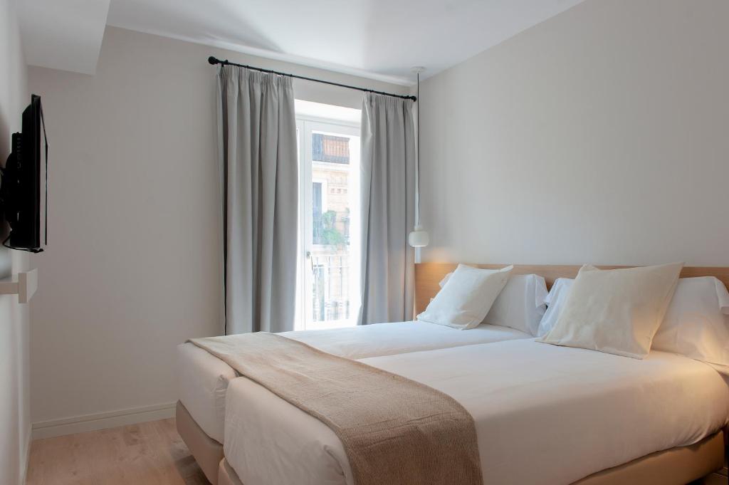 um quarto com uma grande cama branca e uma janela em MH Apartments Central Madrid em Madri