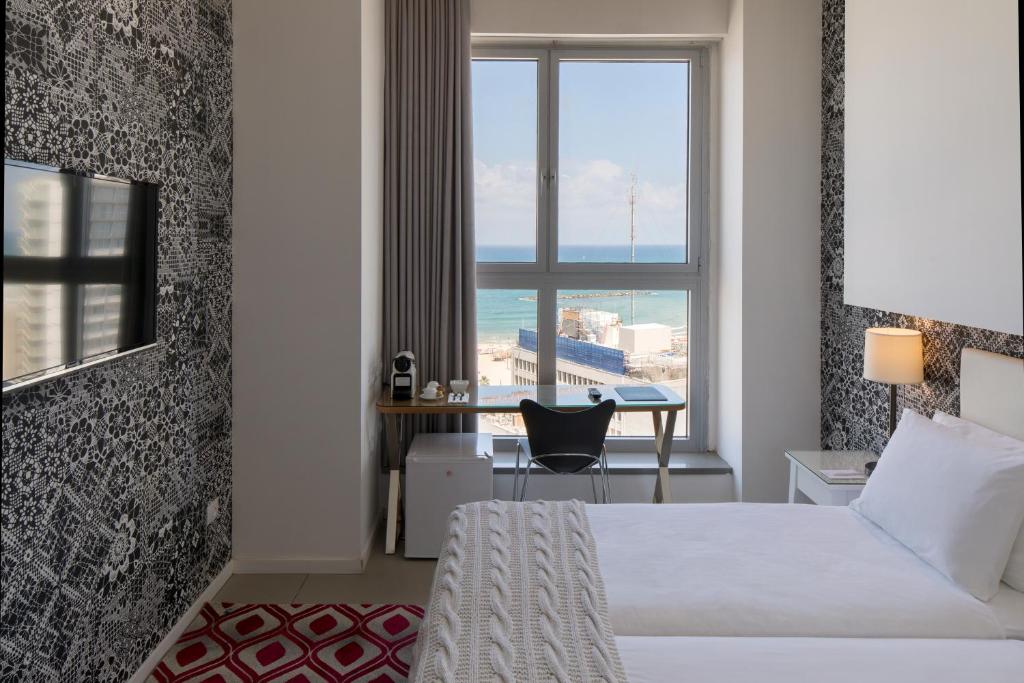 a hotel room with a bed and a desk and a window at Metropolitan Hotel in Tel Aviv
