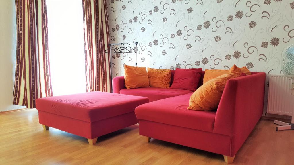 ハーゲンにあるMonteur Apartment Scarlettのリビングルーム(赤いソファ、オットマン付)