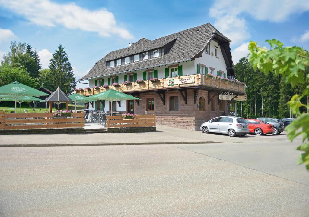 a building with a restaurant with cars parked in a parking lot at Landgasthof Sonne in Alpirsbach