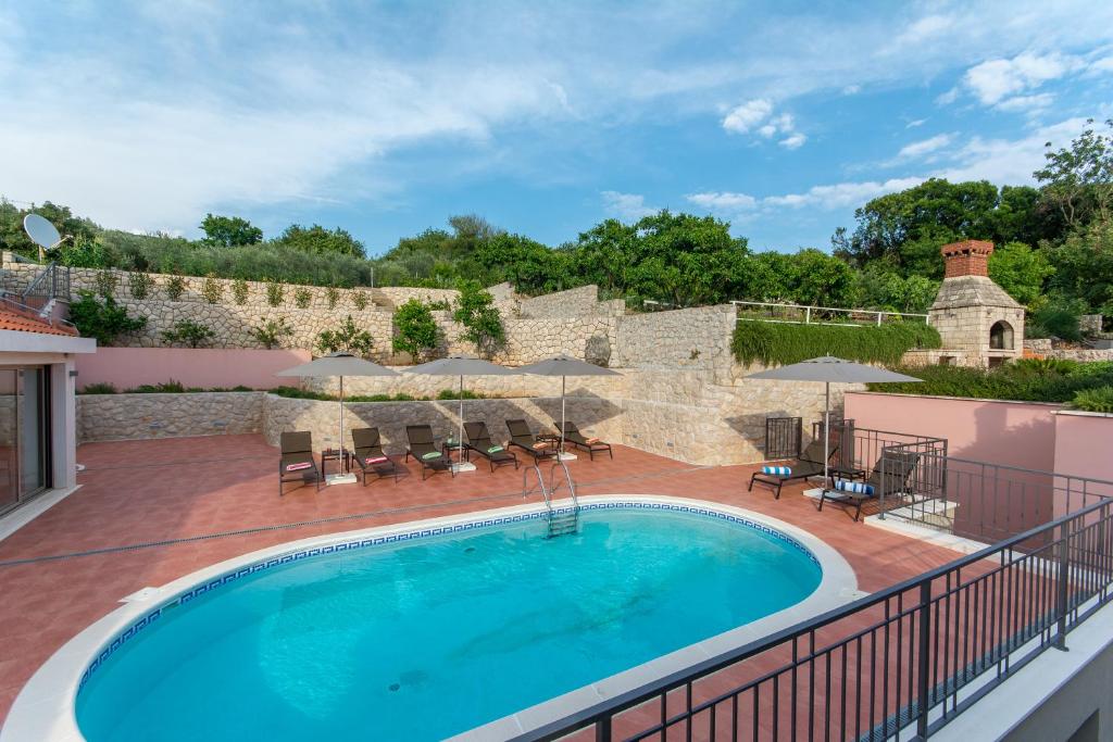 a swimming pool on a deck with a patio with umbrellas at Villa Molunat in Molunat
