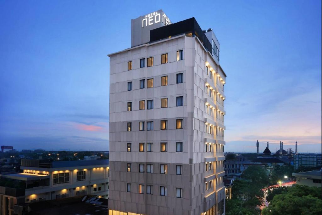 a tall white building with a sign on top of it at Hotel Neo Gajah Mada Pontianak by ASTON in Pontianak