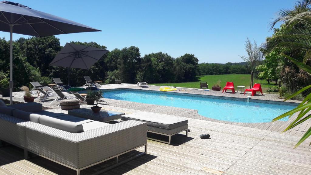 - une piscine avec des canapés, des chaises et un parasol dans l'établissement La Belle Landaise 1809 Gîte Arridoulet 2, à Peyrehorade