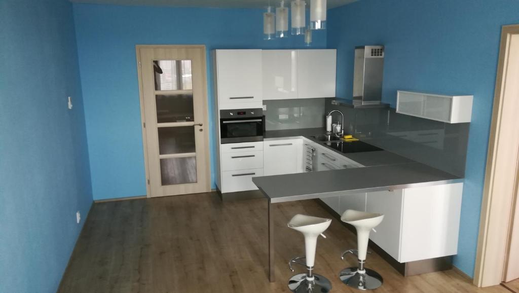 a kitchen with white cabinets and a blue wall at Big Apartment 291 - Rezidence Eliska Prague 9 in Prague