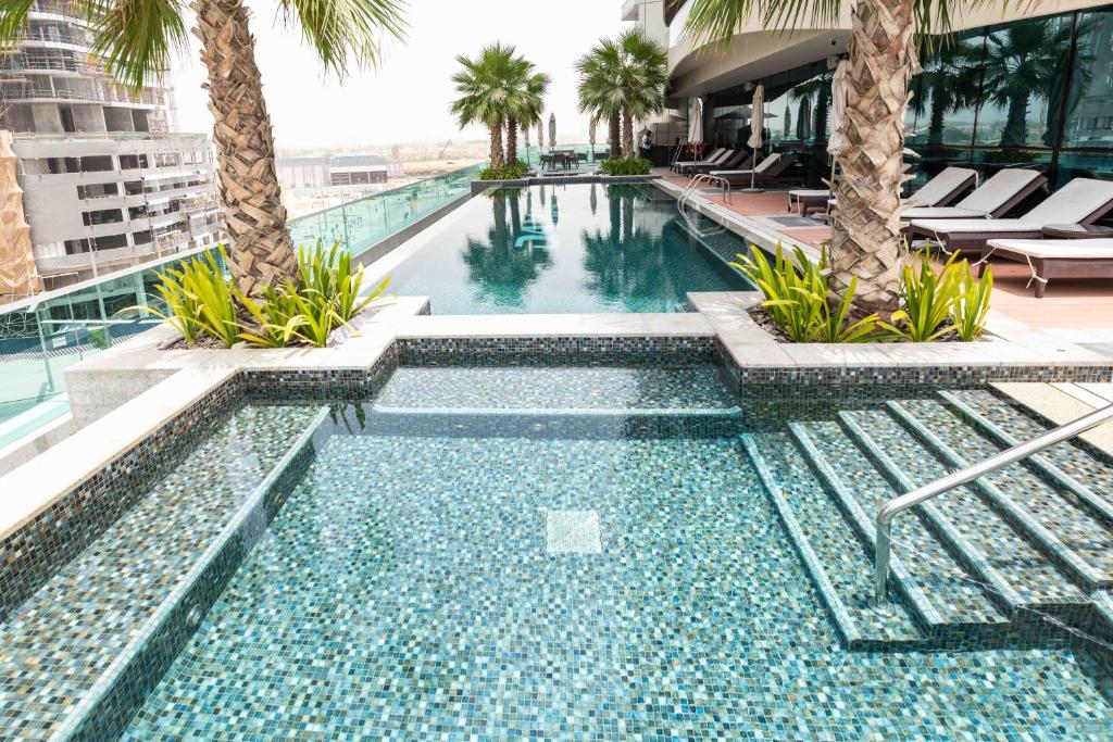 a swimming pool with palm trees in a hotel at DAMAC Upper Crest in Downtown in Dubai