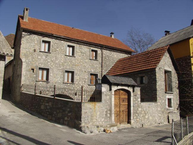 un antiguo edificio de piedra con techo marrón y puerta de madera en Casa Ramón El Pallé, en Sin