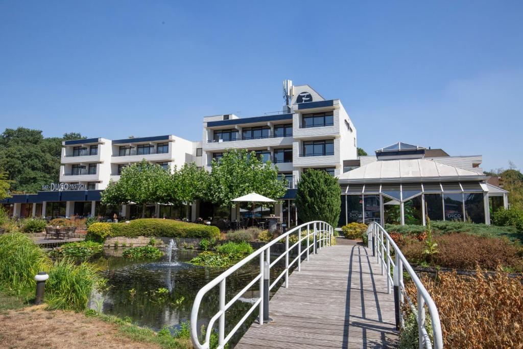 un pont sur un étang en face d'un bâtiment dans l'établissement Fletcher Hotel-Restaurant Frerikshof, à Winterswijk