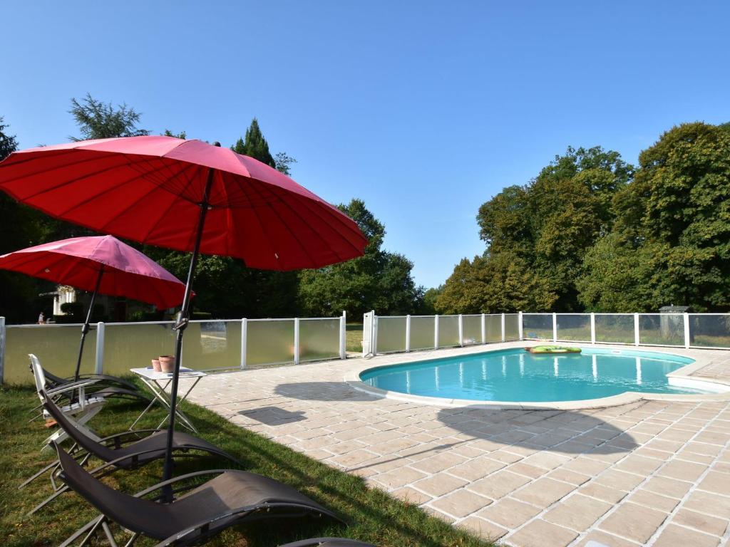 um pátio com um guarda-sol vermelho e uma piscina em Vintage Mansion in Saint Aubin sur Loire with Pool em Bourbon-Lancy