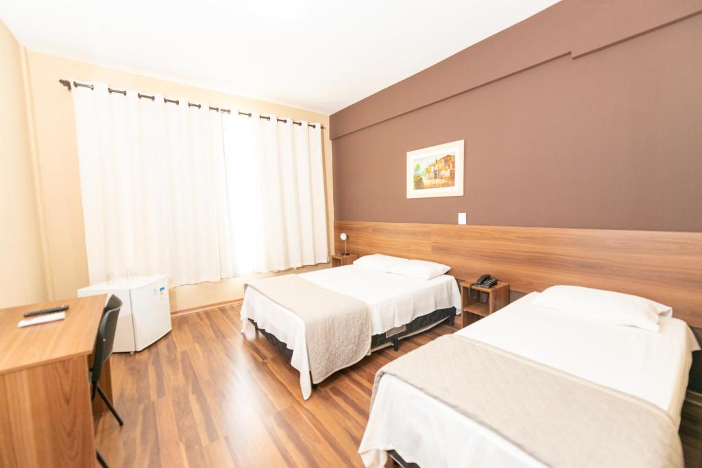 a hospital room with two beds and a desk at Hotel Regional JF in Juiz de Fora