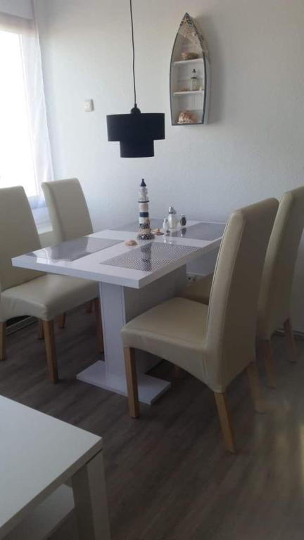 a white dining room table with chairs and a mirror at Ferienwohnung-Suedstrandflair in Burgtiefe auf Fehmarn 