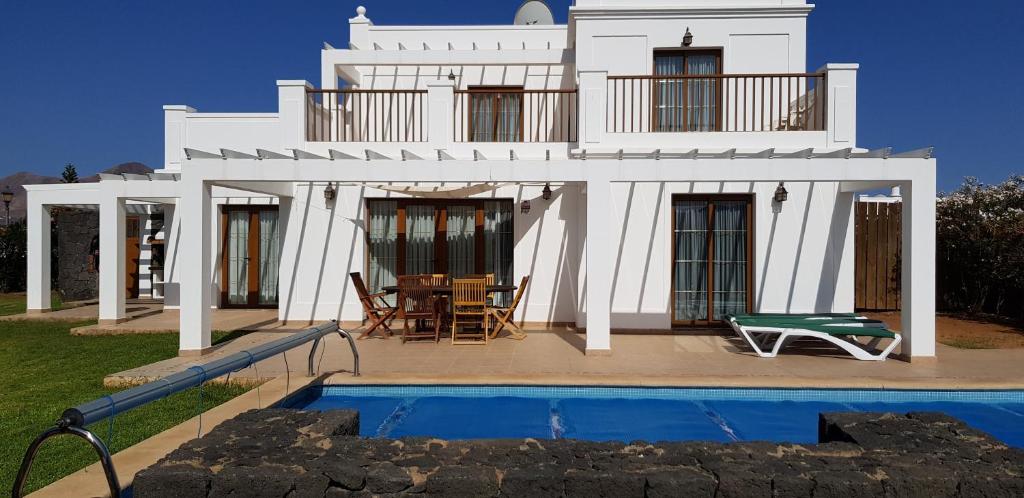a white house with a pool in front of it at Villa Papagayo in Playa Blanca