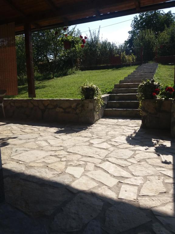 a stone patio with stairs in a yard at Apartmani Maslačak in Vrdnik