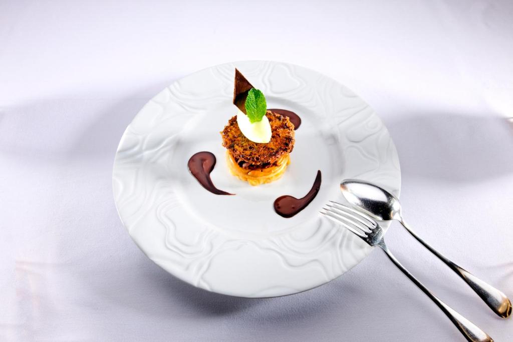 a white plate with a dessert on a table at Hotel Restaurant L&#39;Ami Fritz in Ottrott