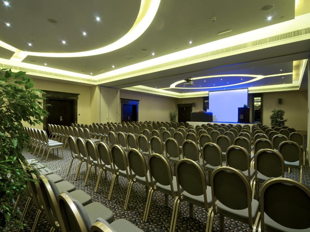 an empty room with chairs and a projection screen at Metropolitan Al Mafraq Hotel in Abu Dhabi