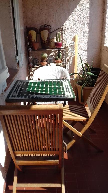 - une table et deux chaises sur une terrasse couverte avec une table verte dans l'établissement Appart au calme, climatisé, avec parking, 2 pas des plages, Hyères le port, à Hyères