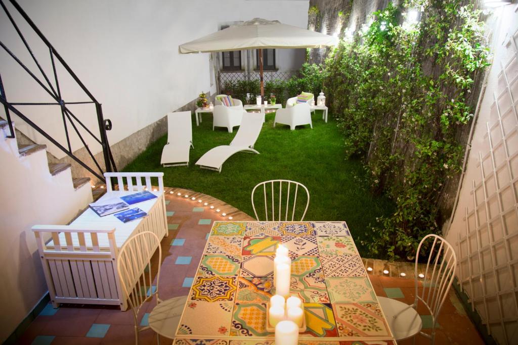 un patio con mesa, sillas y sombrilla en Dimora Salernum, en Salerno