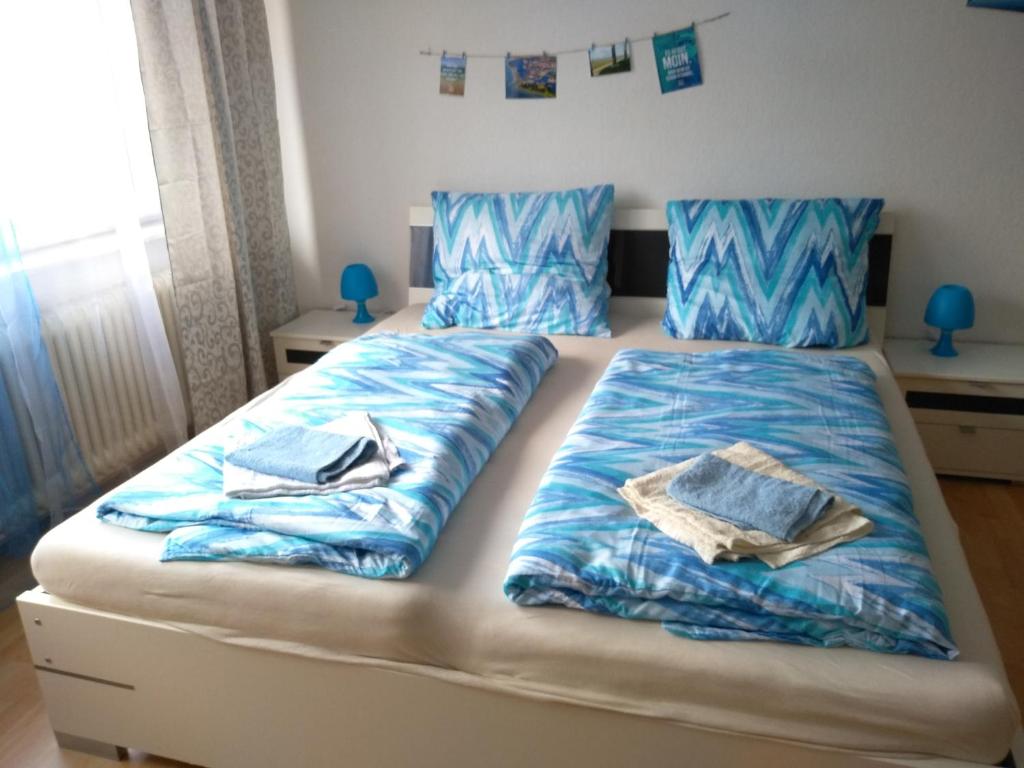 ヴィルヘルムスハーフェンにあるFerienwohnung Nordsee mit E-Bike Verleihのベッドルーム1室(青いシーツが備わるベッド2台付)