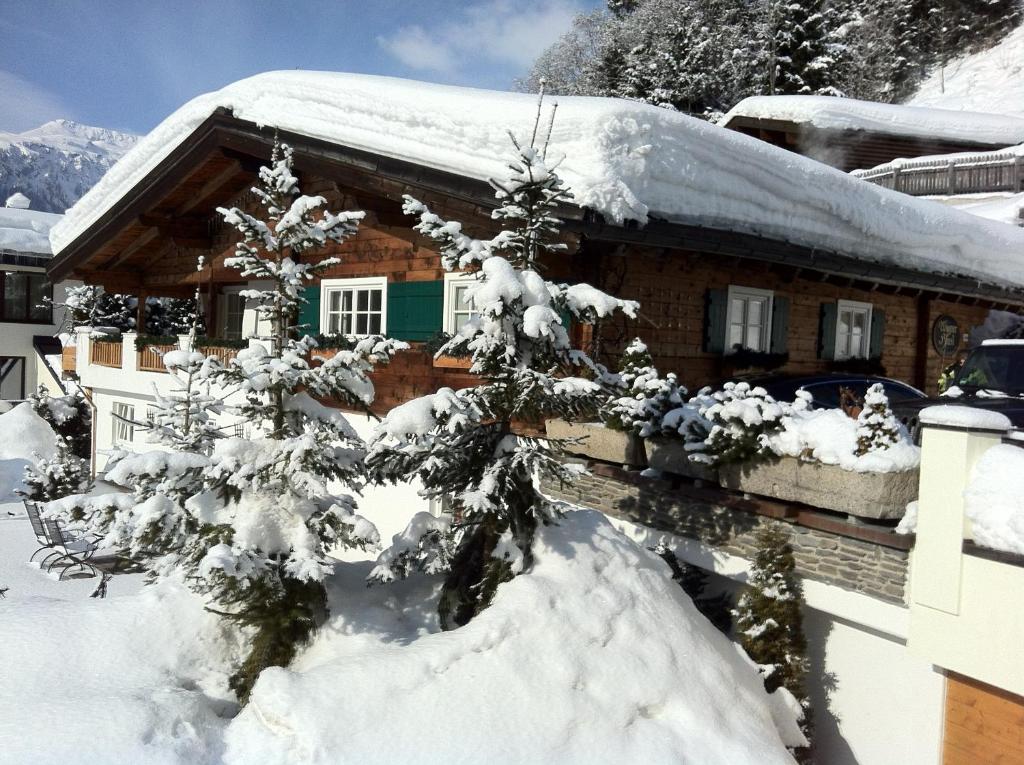 a snow covered house with a snow covered tree at Wagner Häusl in Saalbach-Hinterglemm