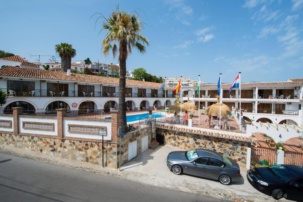 dos coches estacionados frente a un edificio con piscina en Apartamentos La Baranda, en Torremolinos