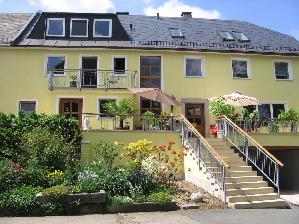 a yellow house with stairs and flowers in front of it at Ferienhof Jungkunz in Schwarzenbach am Wald