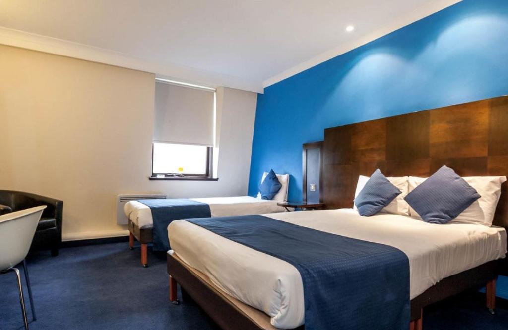a hotel room with two beds and a blue wall at Britannia Edinburgh Hotel in Edinburgh