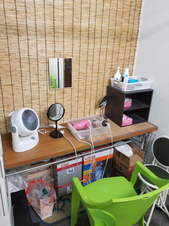 um quarto com uma secretária, uma ventoinha e uma cadeira verde em Kiyamachi Guesthouse em Quioto