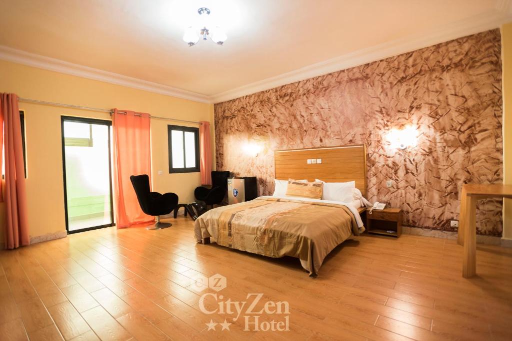 a hotel room with a bed and a chair at Cityzen Hotel in Douala