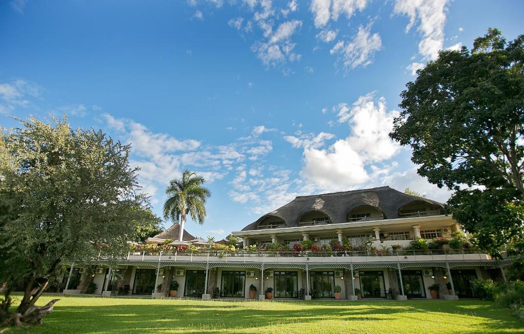 a large building with a palm tree in front of it at Ilala Lodge Hotel in Victoria Falls