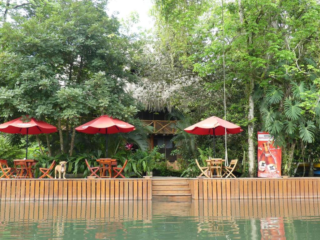 un restaurante con mesas y sombrillas junto a un cuerpo de agua en Hotel Kangaroo y Restaurante, en Río Dulce